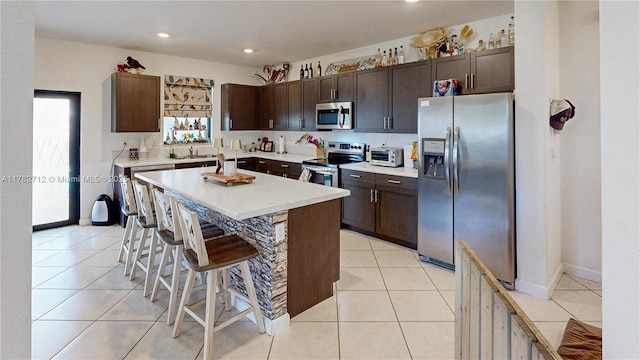 22986 SW 128th Pl, Miami, FL 33170 - kitchen featuring stainless steel appliances, a kitchen breakfast bar, dark brown cabinets, light countertops, and recessed lighting