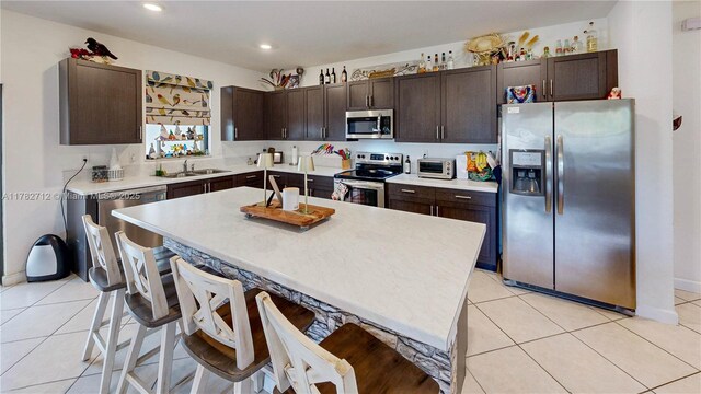 22986 SW 128th Pl, Miami, FL 33170 - kitchen featuring stainless steel appliances, a sink, dark brown cabinetry, a kitchen bar, and light countertops