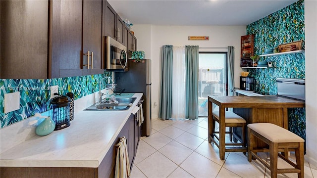 22986 SW 128th Pl, Miami, FL 33170 - kitchen with stainless steel appliances, dark brown cabinetry, light countertops, and light tile patterned floors