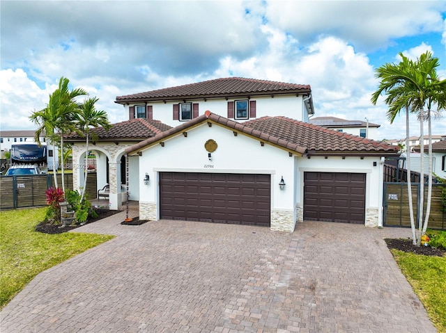 22986 SW 128th Pl, Miami, FL 33170 - mediterranean / spanish house with stone siding, a garage, stucco siding, fence, and decorative driveway