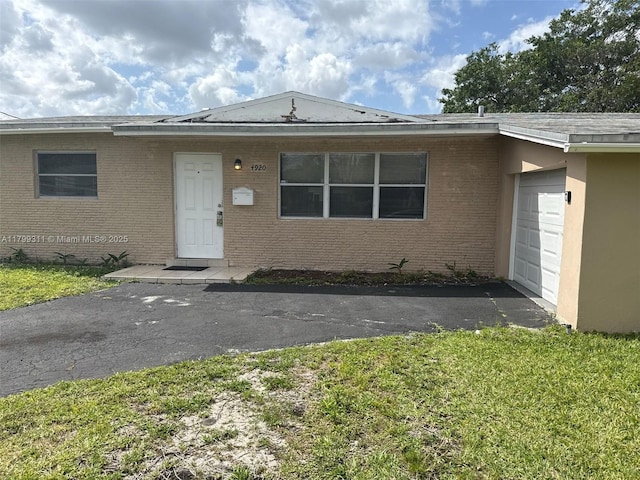 4920 NW 11th St, Lauderhill, FL 33313 - view of front of property with brick siding, a garage, a front yard, and asphalt driveway