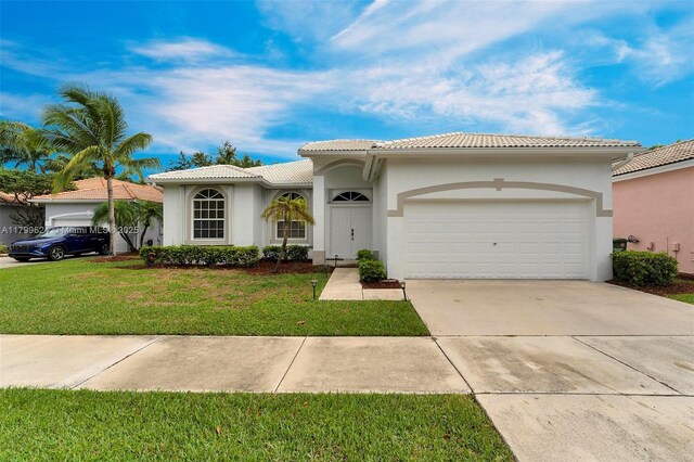 2625 SE 5th Ct, Homestead, FL 33033 - mediterranean / spanish house with a garage, a tiled roof, stucco siding, driveway, and a front yard