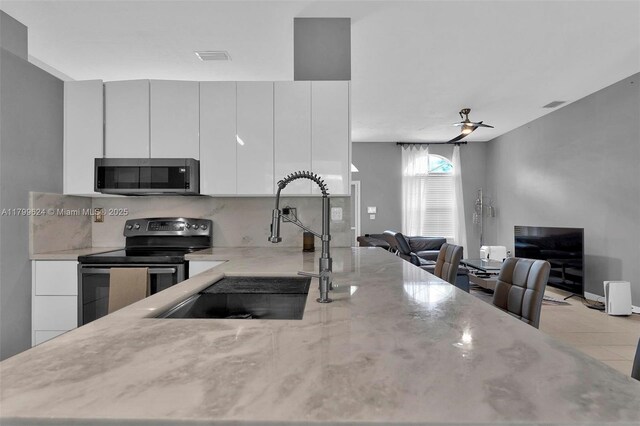 2625 SE 5th Ct, Homestead, FL 33033 - kitchen with stainless steel microwave, electric stove, a sink, light stone counters, and tasteful backsplash