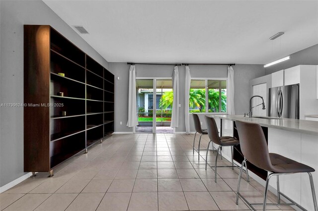 2625 SE 5th Ct, Homestead, FL 33033 - kitchen featuring freestanding refrigerator, a kitchen bar, white cabinetry, light tile patterned floors, and a sink