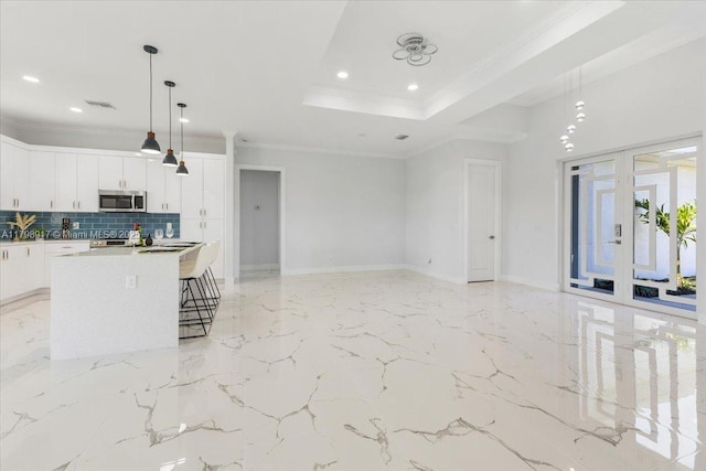 3209 29th St W, Lehigh Acres, FL 33971 - kitchen with stainless steel microwave, a kitchen island, tasteful backsplash, a breakfast bar, and white cabinets