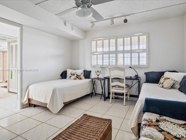 bedroom with light tile patterned floors, multiple windows, rail lighting, and a textured ceiling