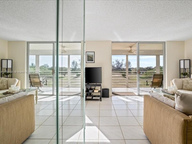living room with a wall of windows, a textured ceiling, light tile patterned flooring, and ceiling fan