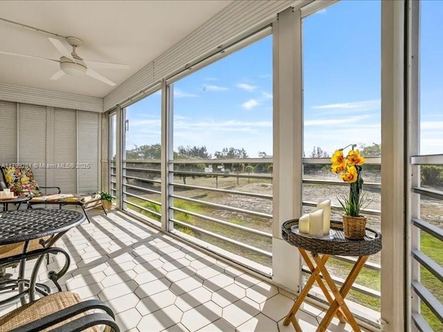 sunroom / solarium with ceiling fan, a water view, and healthy amount of natural light