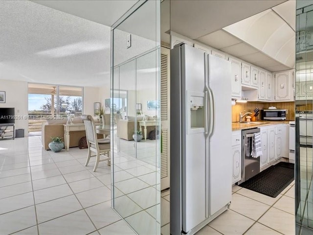 kitchen featuring appliances with stainless steel finishes, light countertops, light tile patterned floors, open floor plan, and white cabinetry