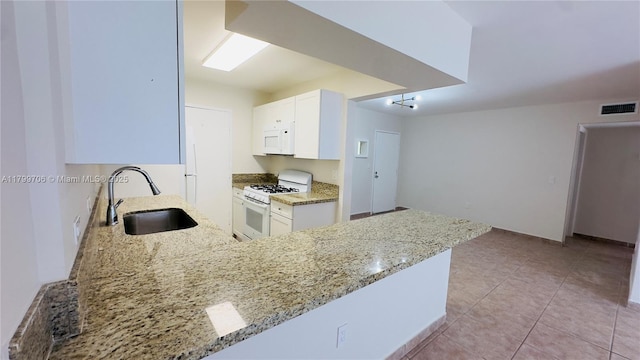 kitchen featuring white appliances, a sink, light stone counters, and white cabinets