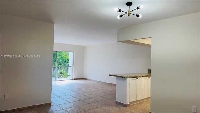 unfurnished room featuring a chandelier, baseboards, and light tile patterned flooring