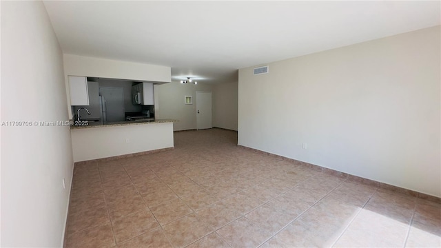 unfurnished living room with a sink and light tile patterned floors