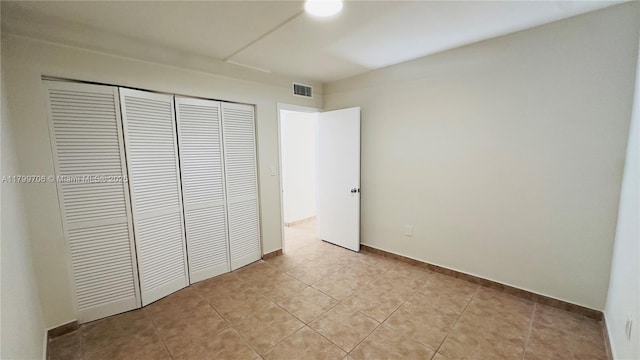 unfurnished bedroom featuring a closet, baseboards, and light tile patterned floors