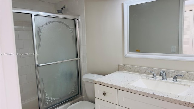 full bath with a shower with door, toilet, and vanity