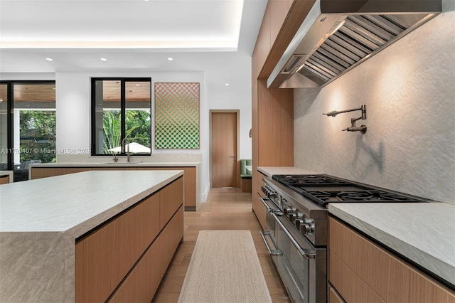 kitchen featuring high end range, premium range hood, light countertops, light wood-style floors, and recessed lighting