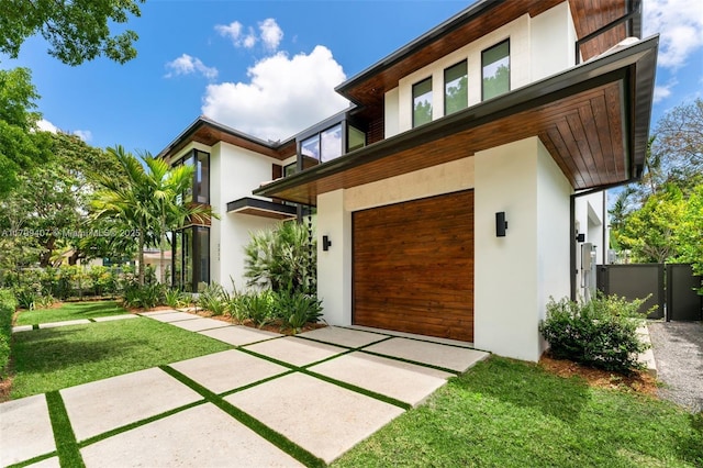 view of front facade with stucco siding, a garage, and a front yard