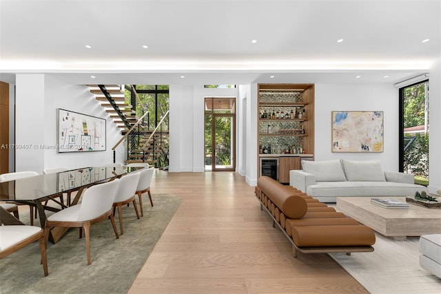 living area featuring a bar, stairs, light wood-type flooring, wine cooler, and recessed lighting