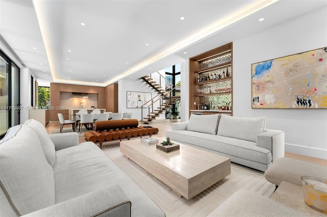 living area with recessed lighting, stairs, a dry bar, built in features, and light wood-style floors