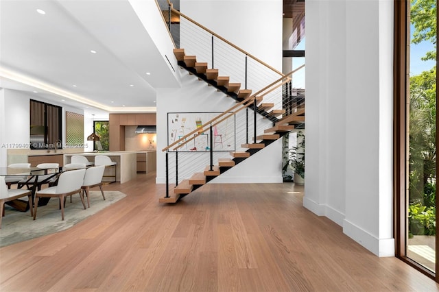 staircase with wood finished floors, recessed lighting, and baseboards