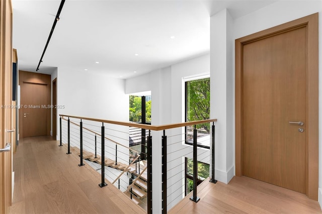 hall with light wood-style floors, an upstairs landing, and recessed lighting