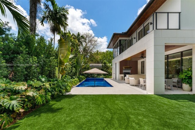 outdoor pool featuring ceiling fan, a patio, a yard, and area for grilling