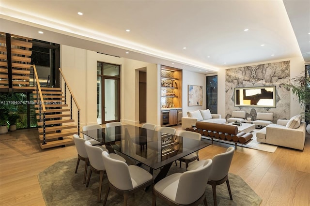 dining area featuring built in features, recessed lighting, wood finished floors, stairs, and a bar