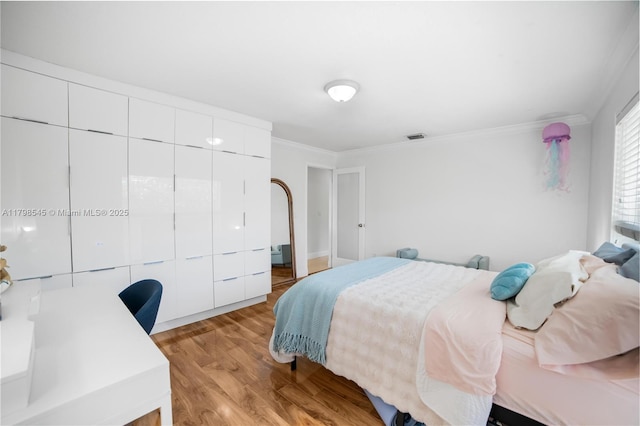 bedroom featuring crown molding, light wood-type flooring, and a closet