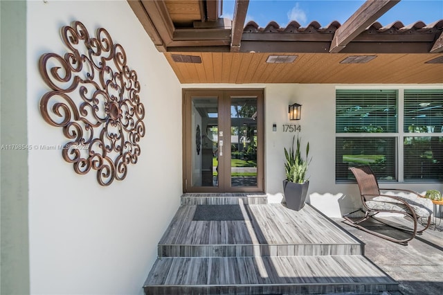 view of exterior entry with french doors and stucco siding