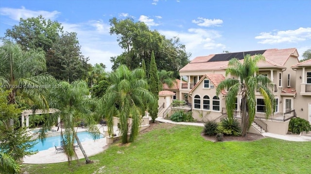 12 Tidewater Dr, Ormond Beach, FL 32174 - rear view of property featuring stairway, a lawn, a balcony, and roof mounted solar panels