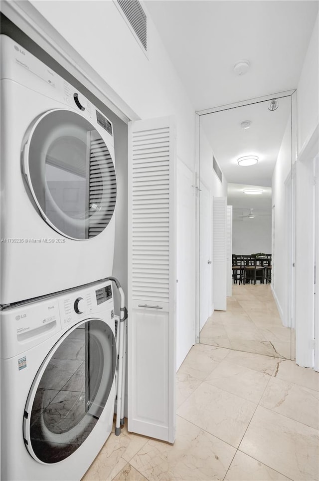 3400 NE 192nd St Unit Ph11, Aventura, FL 33180 - clothes washing area featuring stacked washing machine and dryer and light marble finish floors