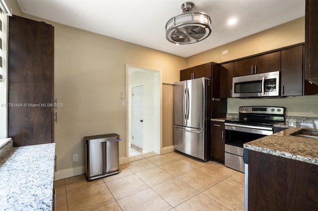 327 S 28th Ave, Hollywood, FL 33020 - kitchen with appliances with stainless steel finishes, dark brown cabinets, light tile patterned floors, baseboards, and dark stone countertops