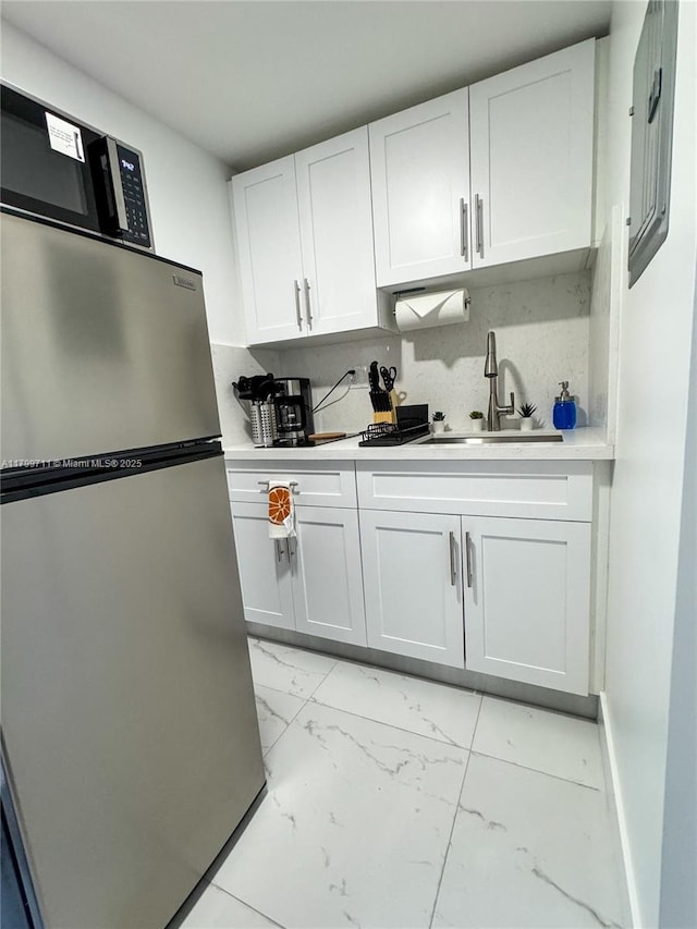 2966 NW 26th St, Miami, FL 33142 - kitchen featuring freestanding refrigerator, light marble finish floors, a sink, light countertops, and white cabinets