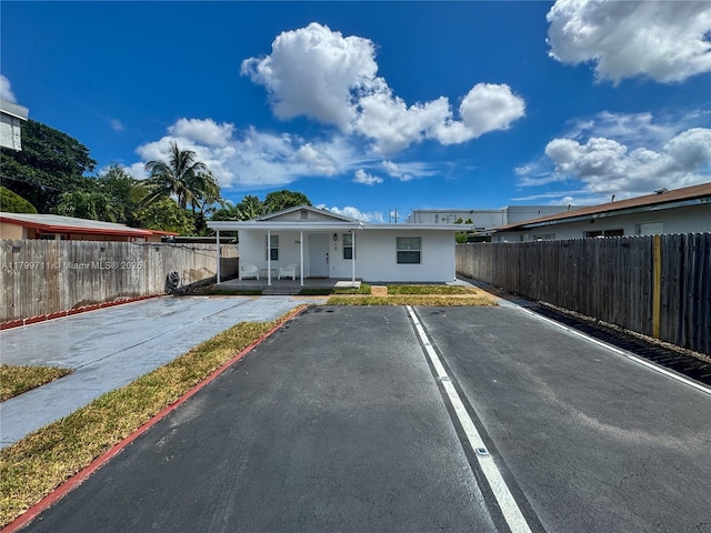 2966 NW 26th St, Miami, FL 33142 - view of front of house featuring a porch, uncovered parking, and fence