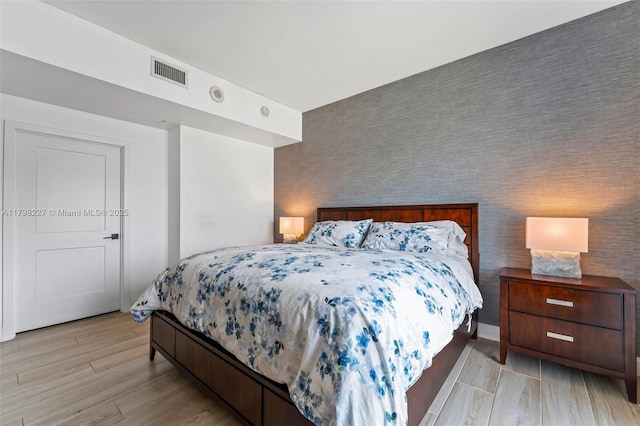 10 Aragon Ave Unit 1107, Coral Gables, FL 33134 - bedroom with an accent wall, light wood-style flooring, and wallpapered walls