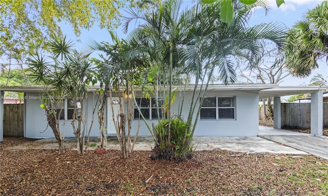 view of front facade with fence, a carport, and stucco siding