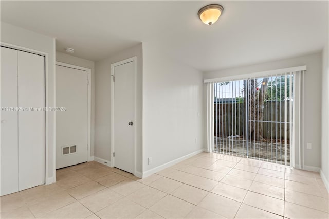 unfurnished bedroom with light tile patterned flooring, baseboards, and access to outside