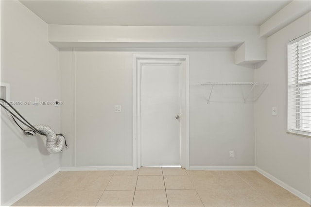 clothes washing area featuring baseboards, light tile patterned floors, washer hookup, and plenty of natural light