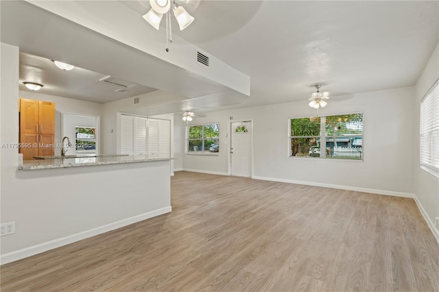 unfurnished living room with a ceiling fan, light wood-style floors, and baseboards