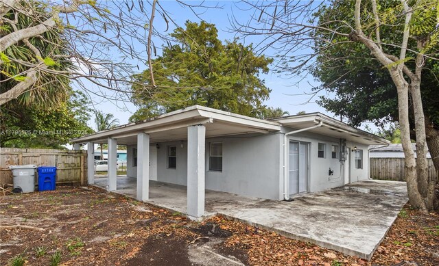 view of side of property featuring fence, a patio area, an attached carport, and stucco siding