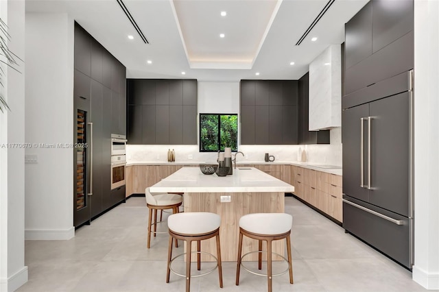 11143 NE 8th Ave, Biscayne Park, FL 33161 - kitchen with modern cabinets, built in fridge, a kitchen bar, a kitchen island with sink, and decorative backsplash
