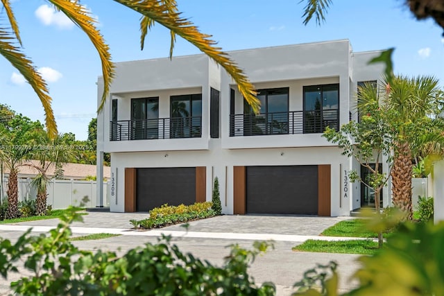 1320 NE 16th Ave, Fort Lauderdale, FL 33304 - contemporary house with stucco siding, a balcony, a garage, fence, and driveway