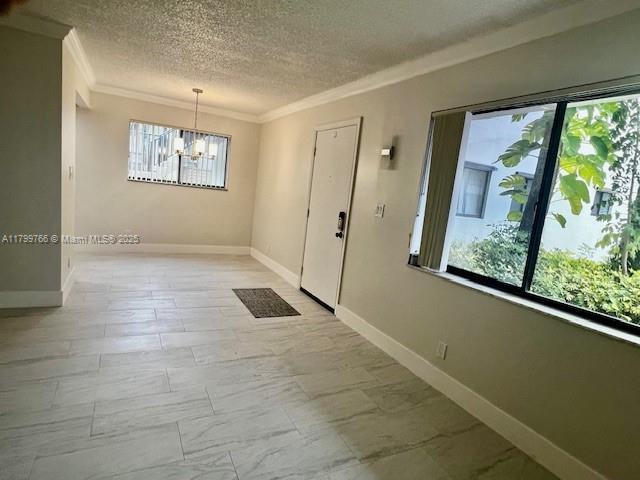 9920 NW 68th Pl Unit 103, Tamarac, FL 33321 - entryway featuring ornamental molding, a textured ceiling, a chandelier, and baseboards