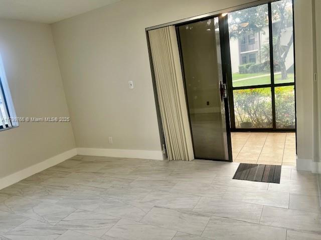 9920 NW 68th Pl Unit 103, Tamarac, FL 33321 - empty room with healthy amount of natural light, baseboards, and marble finish flooring