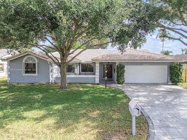 15827 Waverly Mnr, Davie, FL 33331 - view of front facade featuring a garage, stucco siding, a tiled roof, decorative driveway, and a front lawn