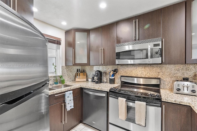 1750 W 46th St Unit 528, Hialeah, FL 33012 - kitchen with appliances with stainless steel finishes, dark brown cabinetry, decorative backsplash, glass insert cabinets, and recessed lighting