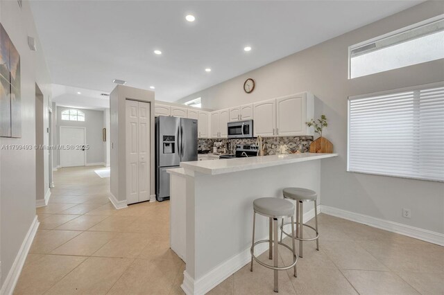 5020 Ibis Ct, Coconut Creek, FL 33073 - kitchen featuring stainless steel appliances, light tile patterned floors, a peninsula, a kitchen bar, and recessed lighting