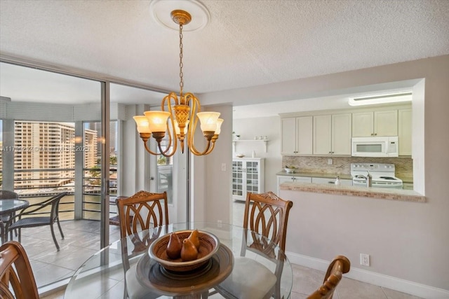 100 Golden Isles Dr Unit 1105, Hallandale Beach, FL 33009 - dining space featuring a chandelier, light tile patterned floors, a textured ceiling, and baseboards