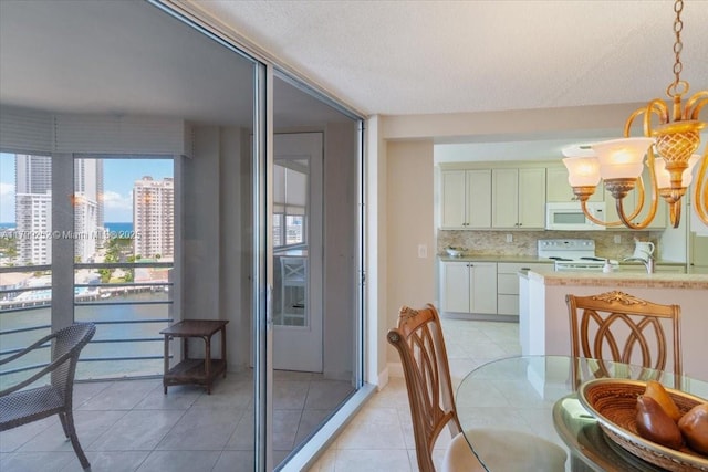 100 Golden Isles Dr Unit 1105, Hallandale Beach, FL 33009 - dining space with a chandelier, light tile patterned floors, a city view, and a textured ceiling