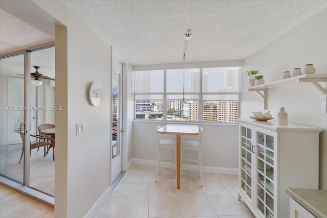 100 Golden Isles Dr Unit 1105, Hallandale Beach, FL 33009 - dining room with a textured ceiling, ceiling fan, baseboards, and light tile patterned floors