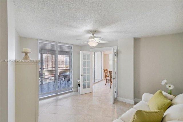 100 Golden Isles Dr Unit 1105, Hallandale Beach, FL 33009 - living room featuring baseboards, light tile patterned floors, french doors, a ceiling fan, and a textured ceiling